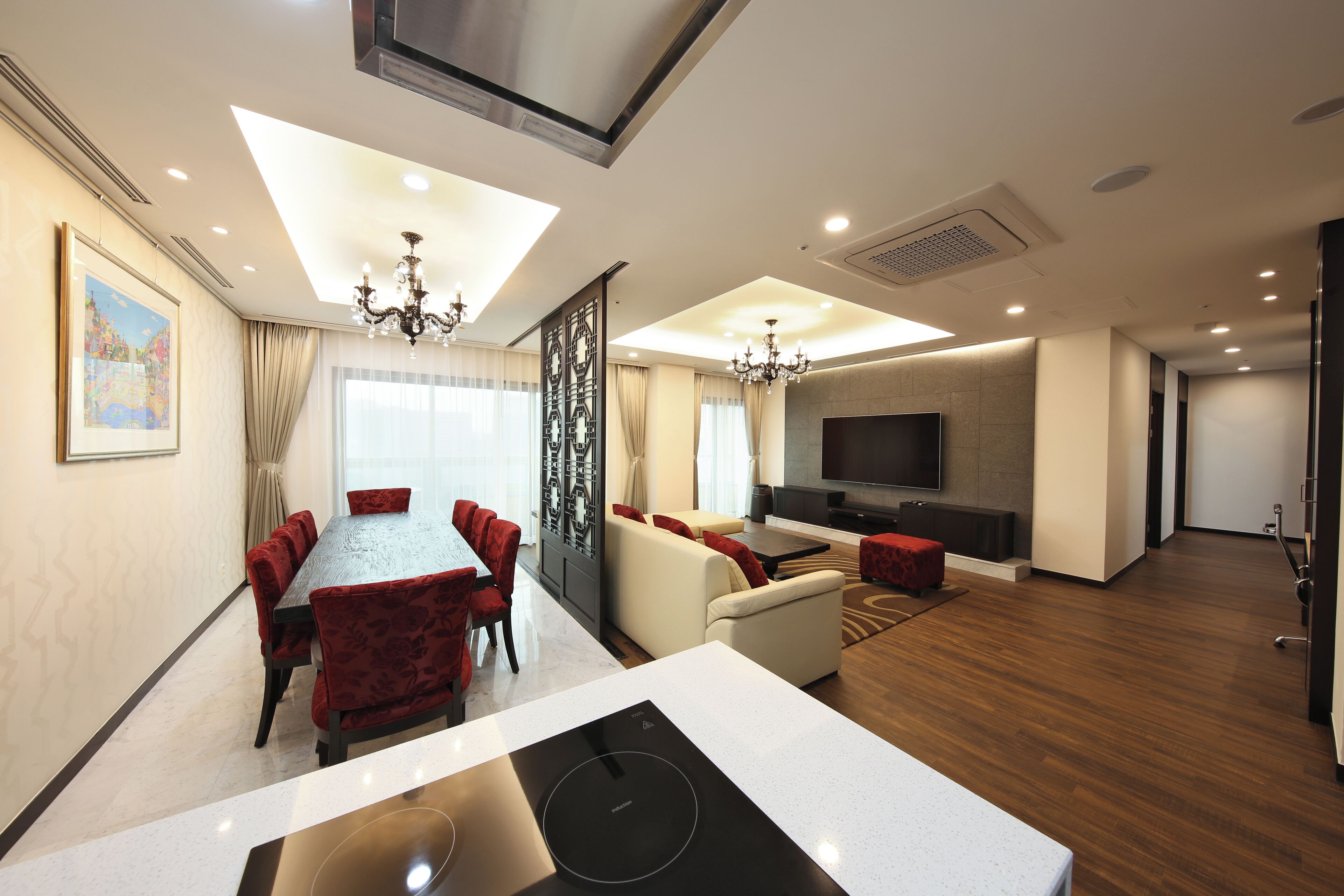 A modern hotel room with a dining area, a living room, and a TV.