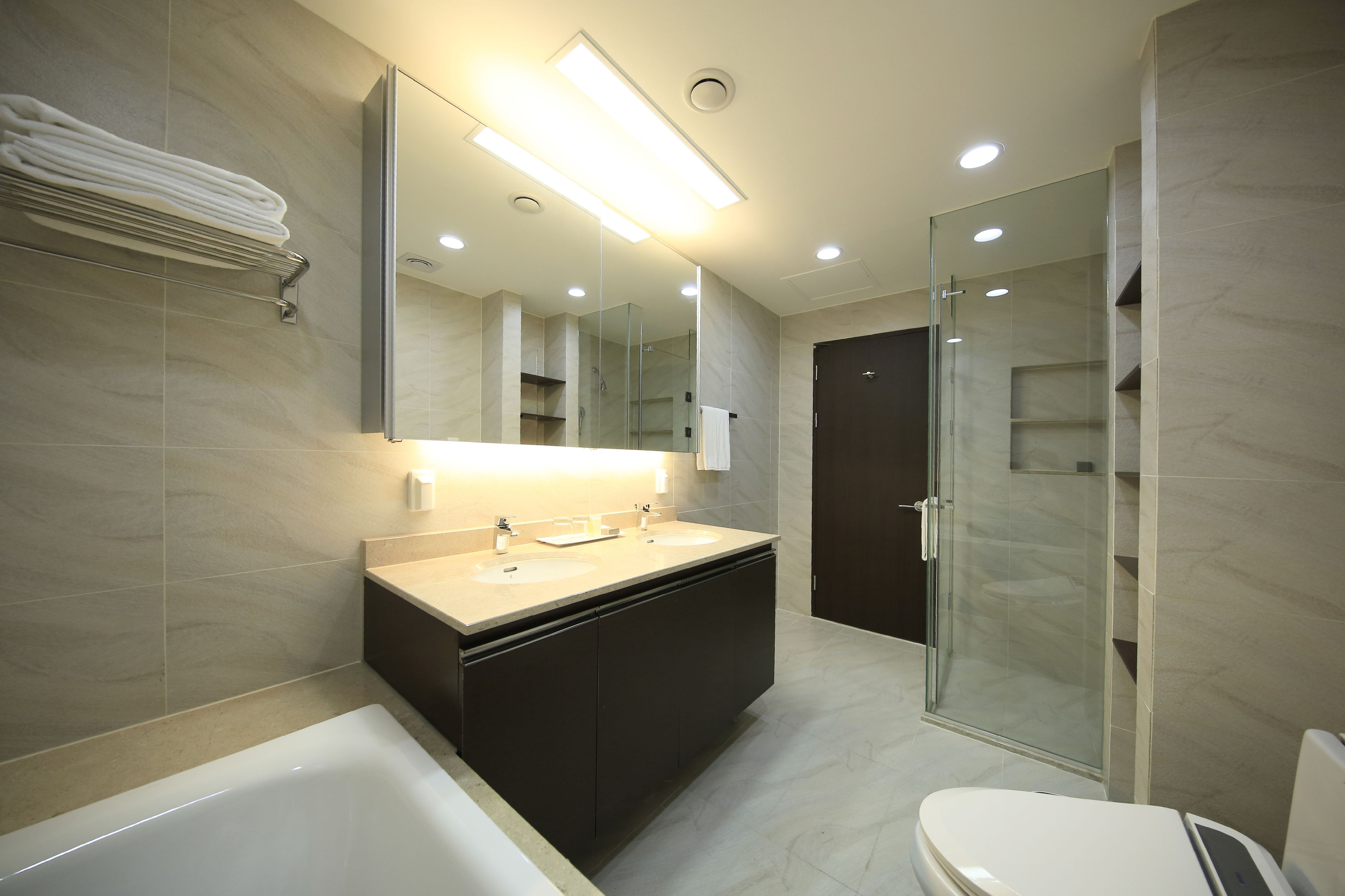 Un baño moderno con una bañera, dos lavamanos, un inodoro y una cabina de ducha de vidrio.