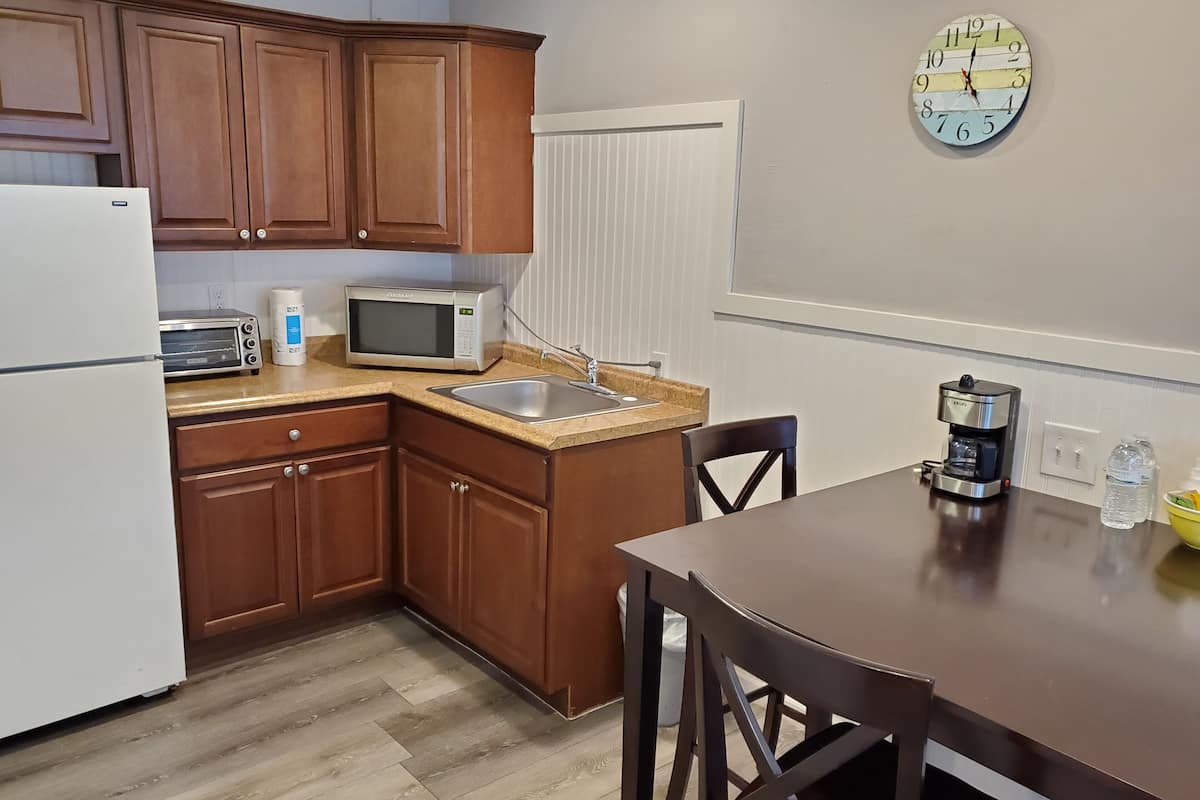 A compact kitchen with wooden cabinets, a microwave, a toaster, a sink, and a coffee maker.