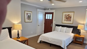 Habitació d'hotel amb dos llits, un amb capçalera de fusta, una porta amb finestreta i dues taules de nit amb làmpades.