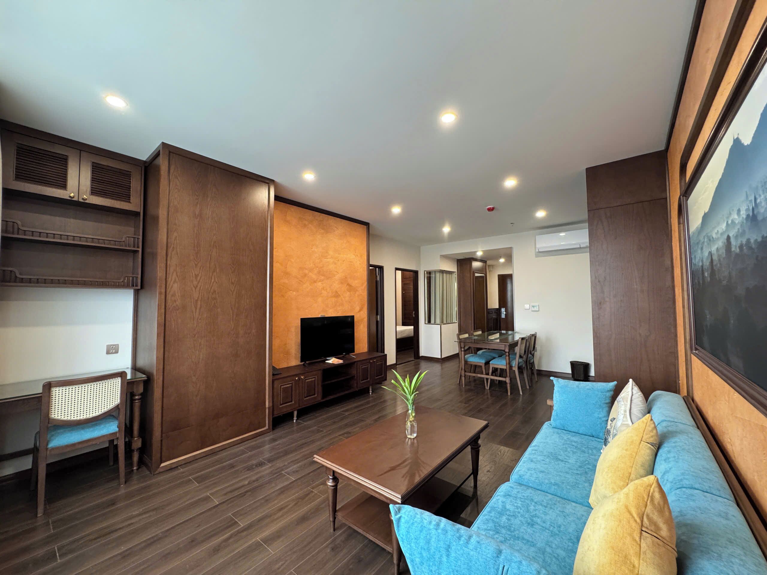 A modern living room with a wooden floor, a blue sofa, a coffee table, and a TV.