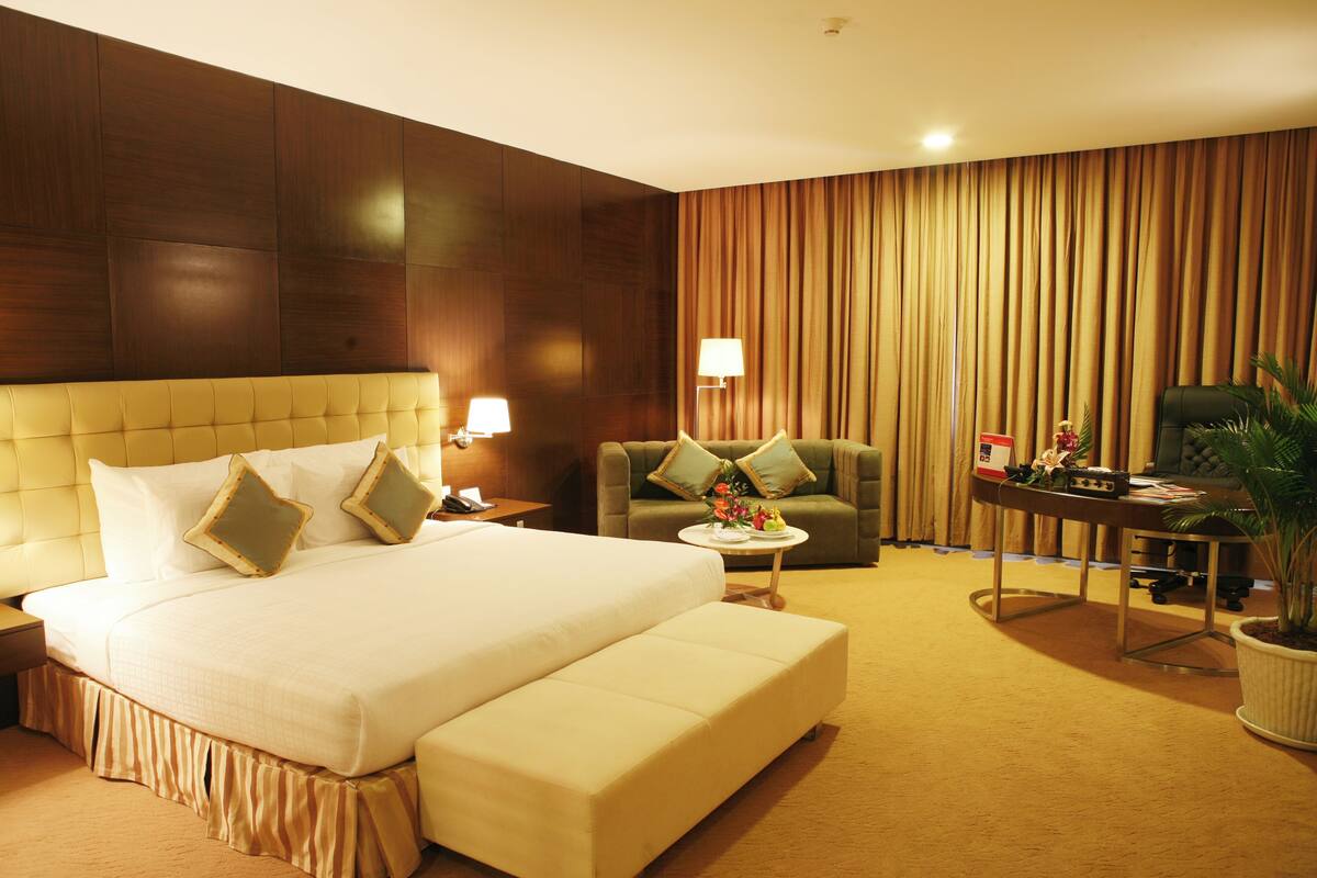 Une chambre d’hôtel avec un grand lit, un canapé, une petite table et un bureau.