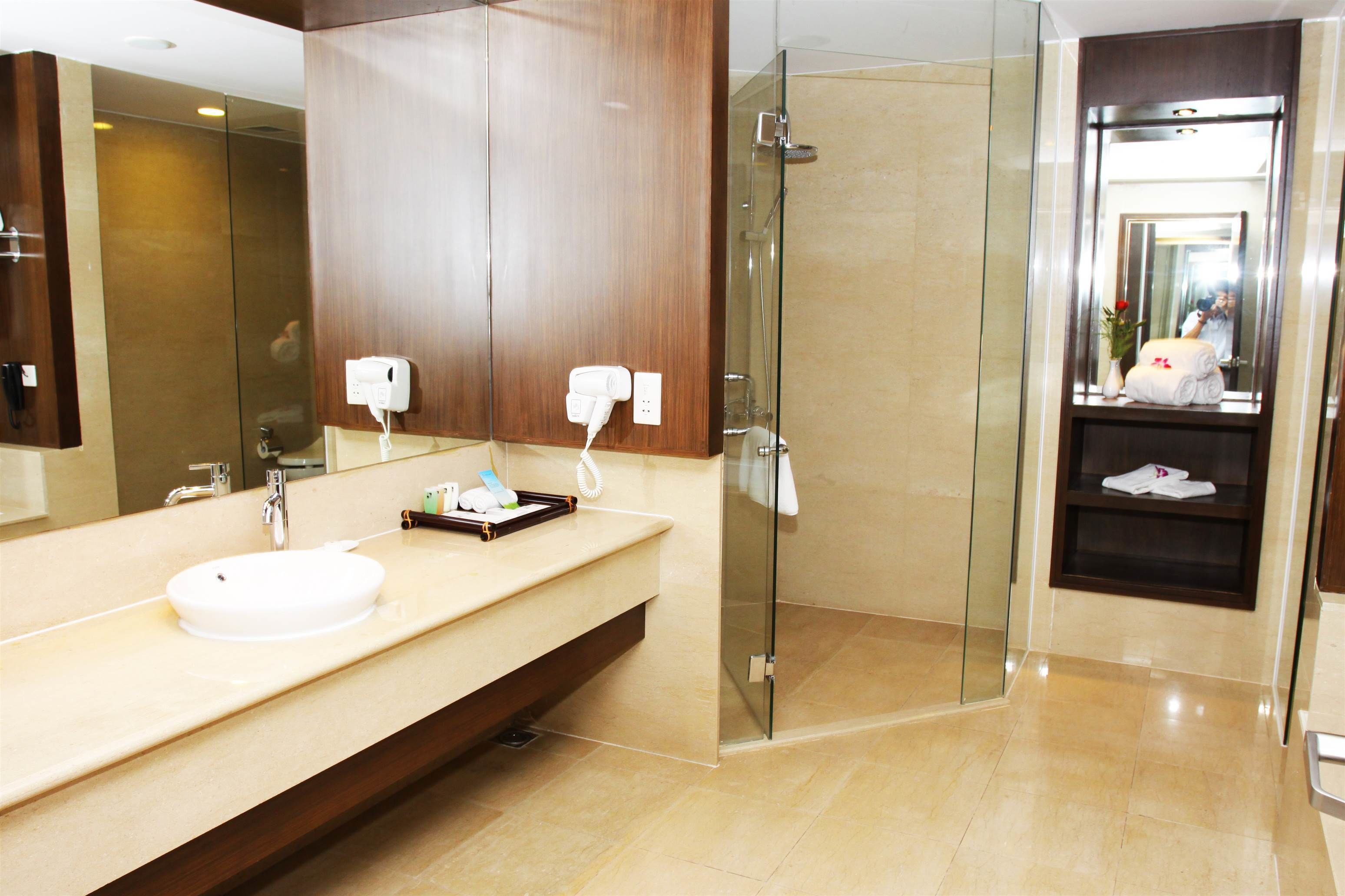 A modern bathroom with a large mirror, a sink, and a glass-enclosed shower.