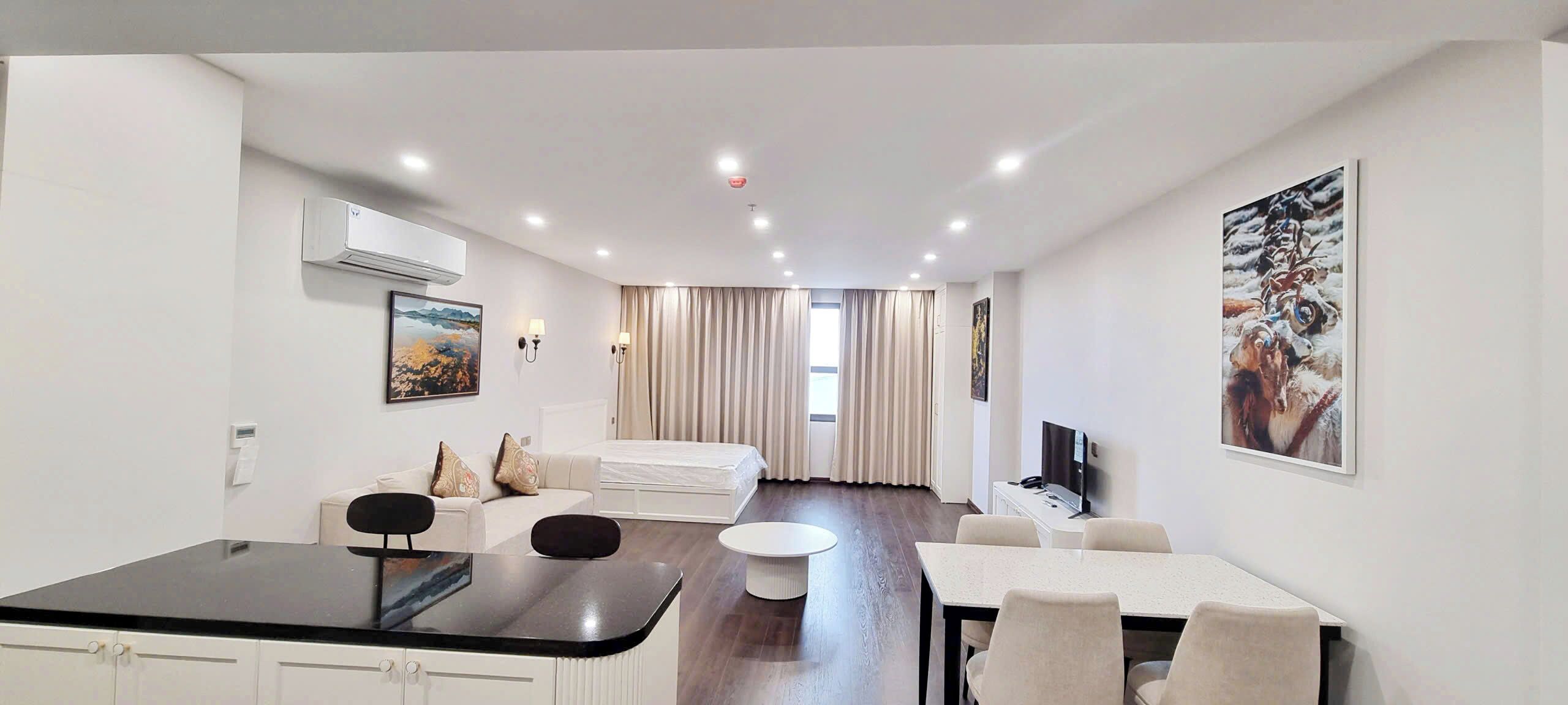 Une chambre d’hôtel moderne avec un coin repas, un canapé, une télévision et un tableau au mur.