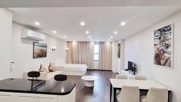 Une chambre d’hôtel moderne avec un coin repas, un canapé, une télévision et un tableau au mur.