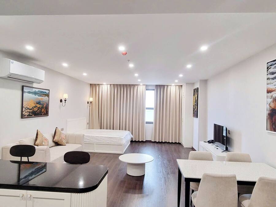 Une chambre d’hôtel moderne avec un coin repas, un canapé, une télévision et un tableau au mur.