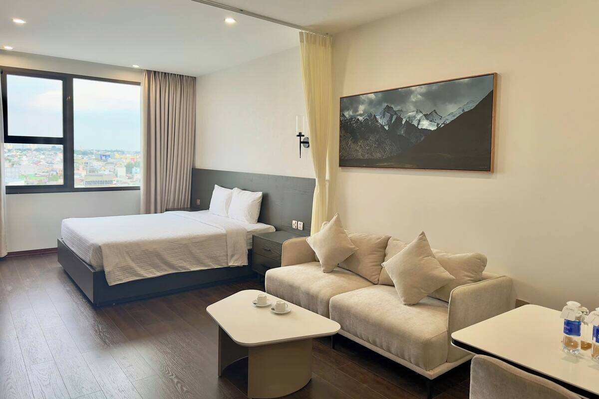 Une chambre d’hôtel avec un lit, un canapé, une petite table et un tableau au mur.