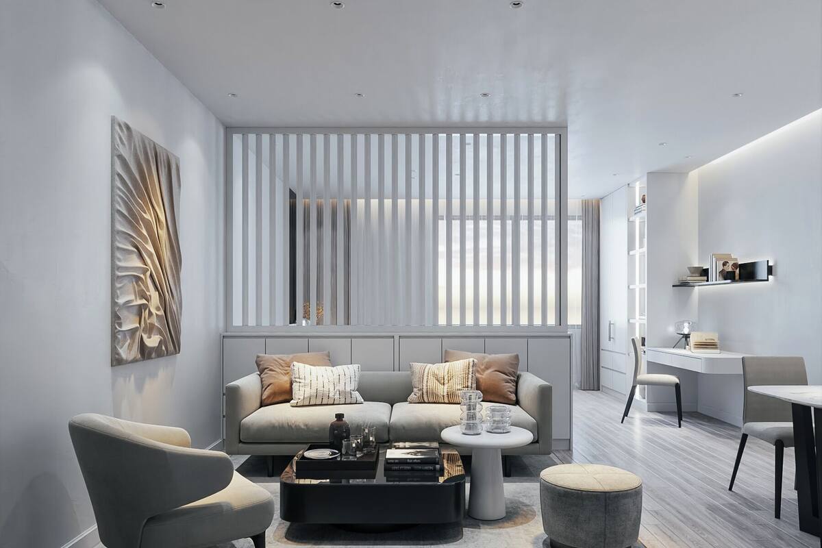 A modern living room with a grey sofa, a coffee table, and a dining area with a white table and chairs.
