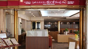 A restaurant with a wooden counter and seating area. There is a menu stand with food items displayed. - Hotel Resol Sasebo (Sasebo)