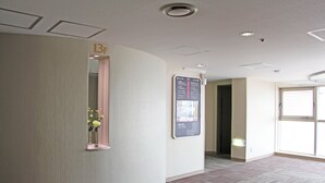 A hotel reception area with a curved wall, a reception desk, a wall-mounted information board, and a door leading to another room. - Hotel Resol Sasebo (Sasebo)