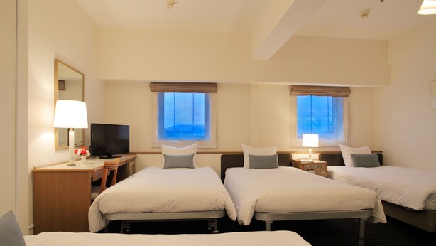 A hotel room with three beds, a desk with a TV, and two windows with curtains. - Hotel Resol Sasebo (Sasebo)