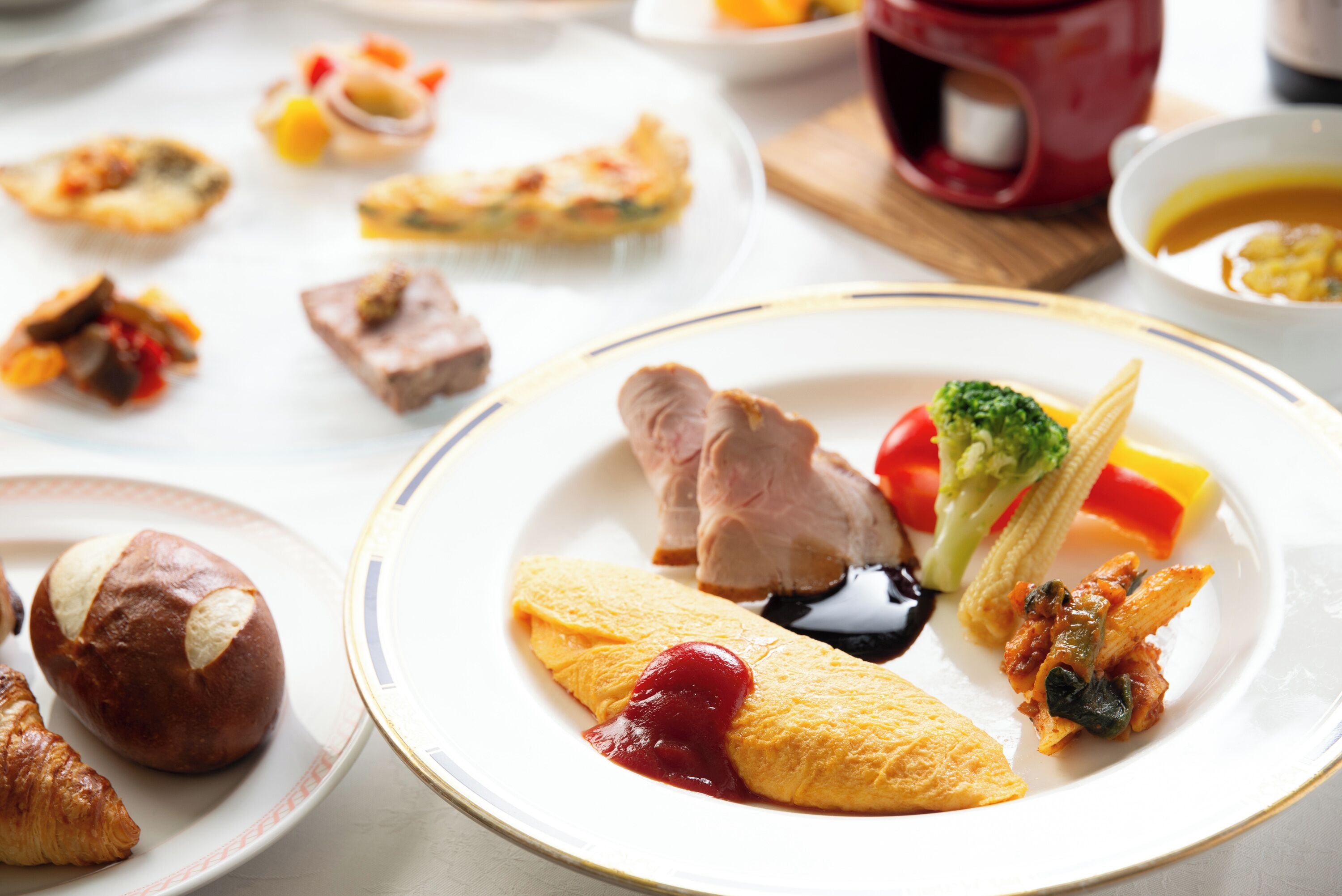 Une variété de plats sont disposés sur la table, notamment une assiette contenant un croissant, une tranche de pain et un morceau de viande.