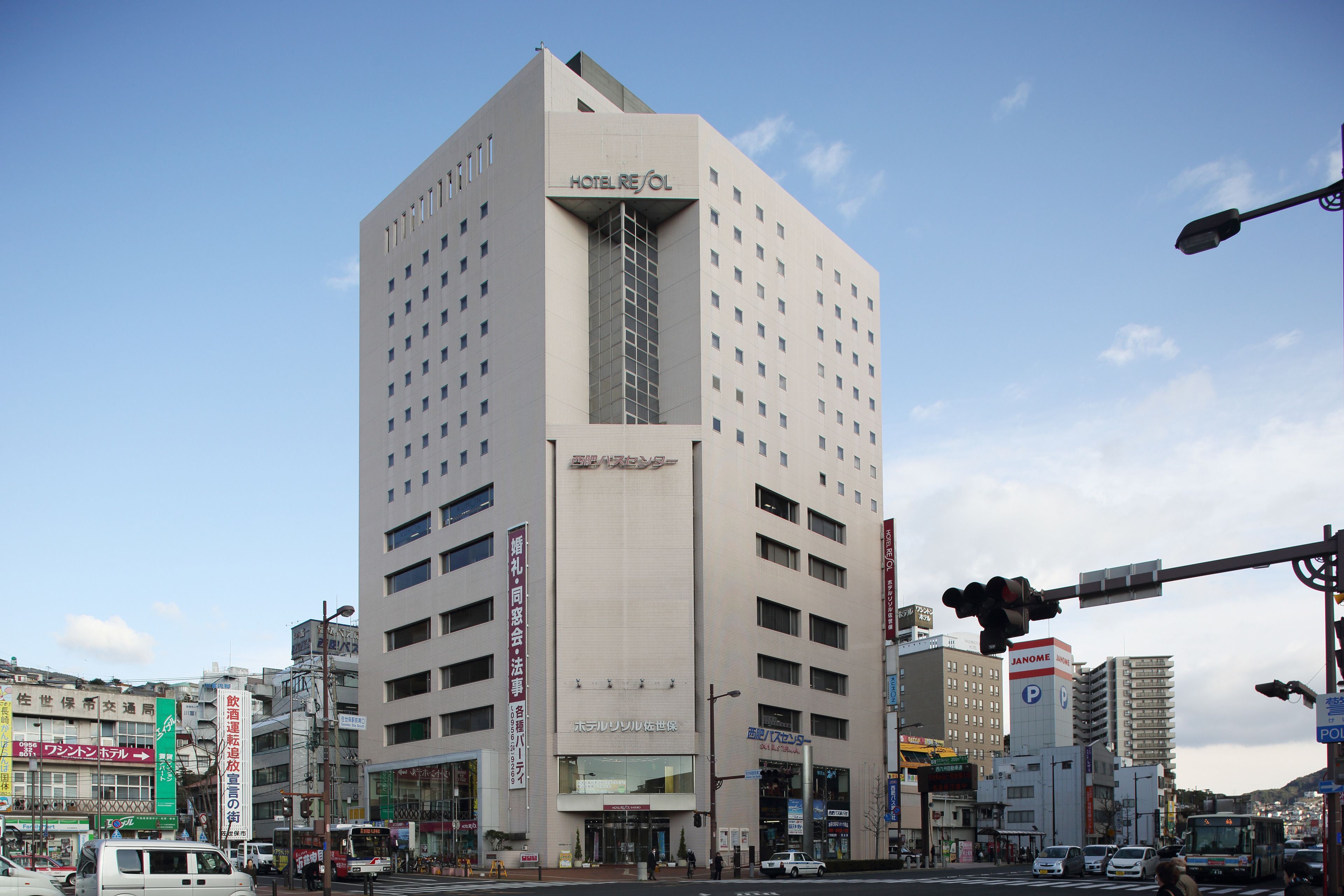 A modern hotel with a prominent entrance, multiple floors, and a clear sky.