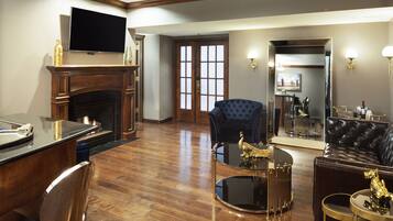 Un salón espacioso con chimenea, un televisor montado encima y una zona de estar cómoda con un sofá y sillones.