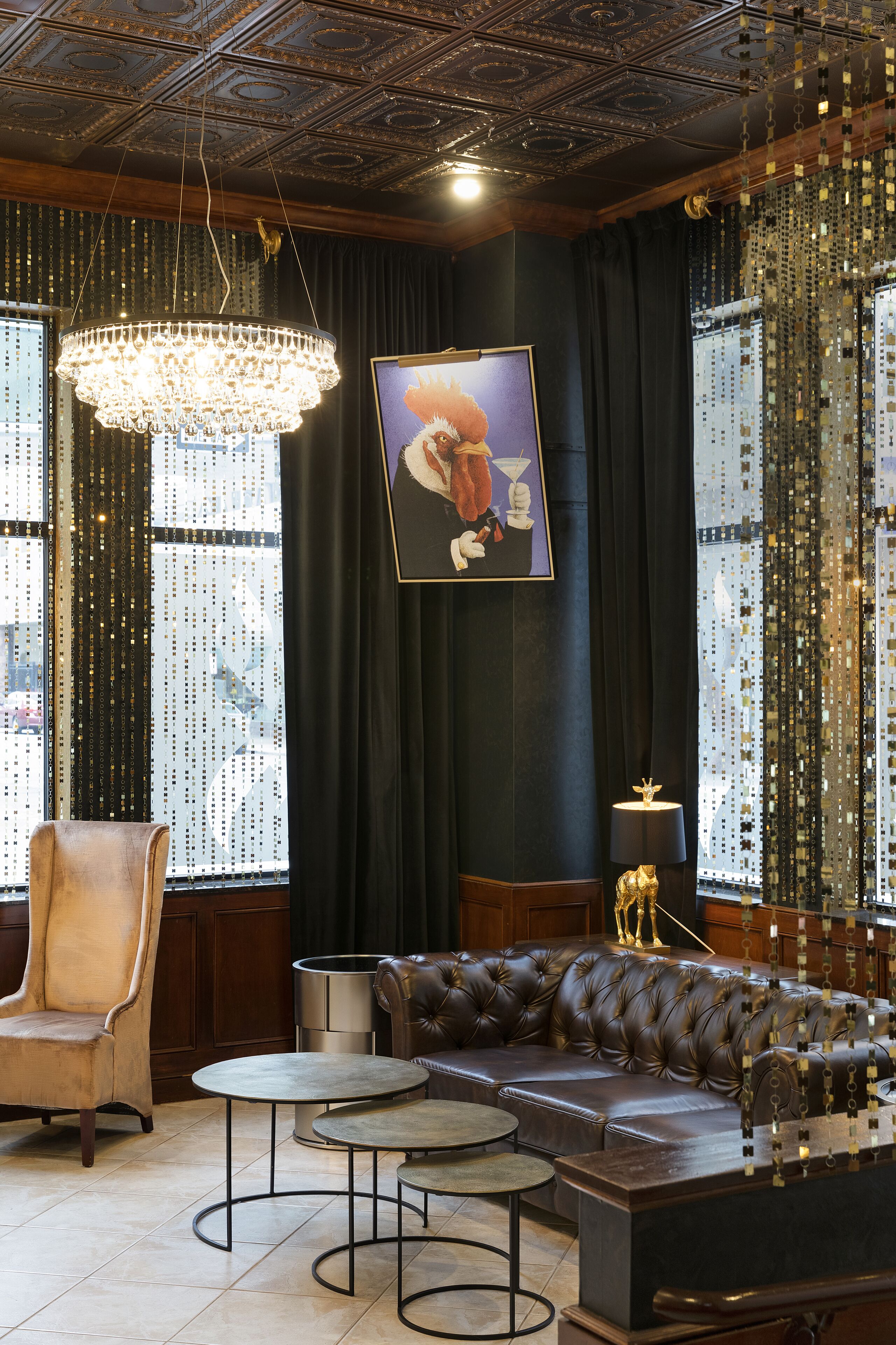 A luxurious room with a large chandelier, a leather sofa, and a framed artwork on the wall.