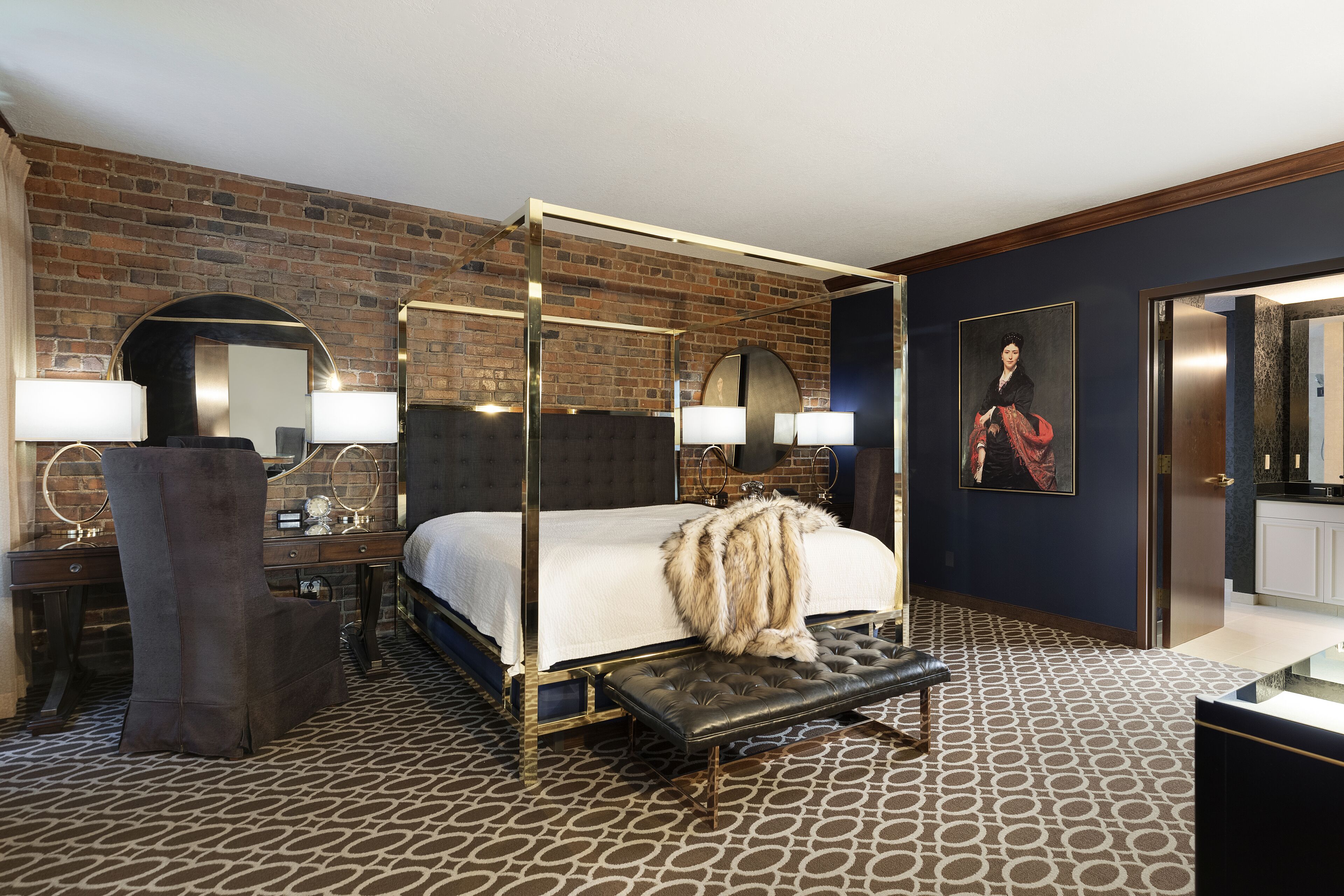 Ein Bett mit Baldachin, eine Felldecke, ein großer Spiegel und ein Gemälde an der Wand.