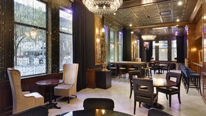 A spacious hotel lobby with high ceilings, ornate chandeliers, and a bar area. - Des Lux Hotel (Des Moines)