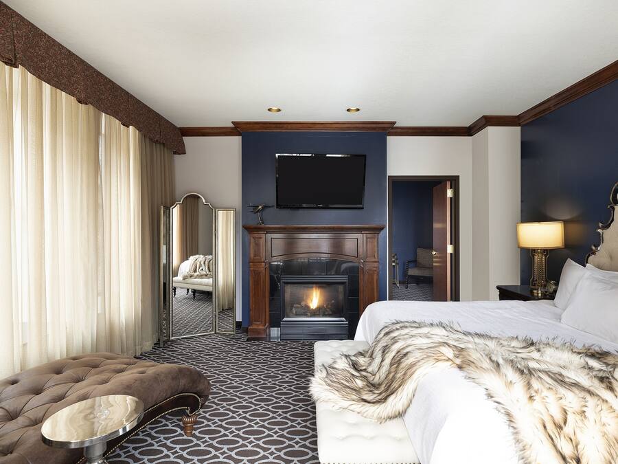 Een hotelkamer met een open haard, een groot bed, een bank en een televisie.