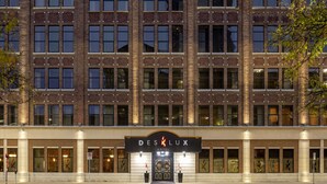 A hotel facade with a brick exterior, large windows, and a prominent entrance sign. - Des Lux Hotel (Des Moines)