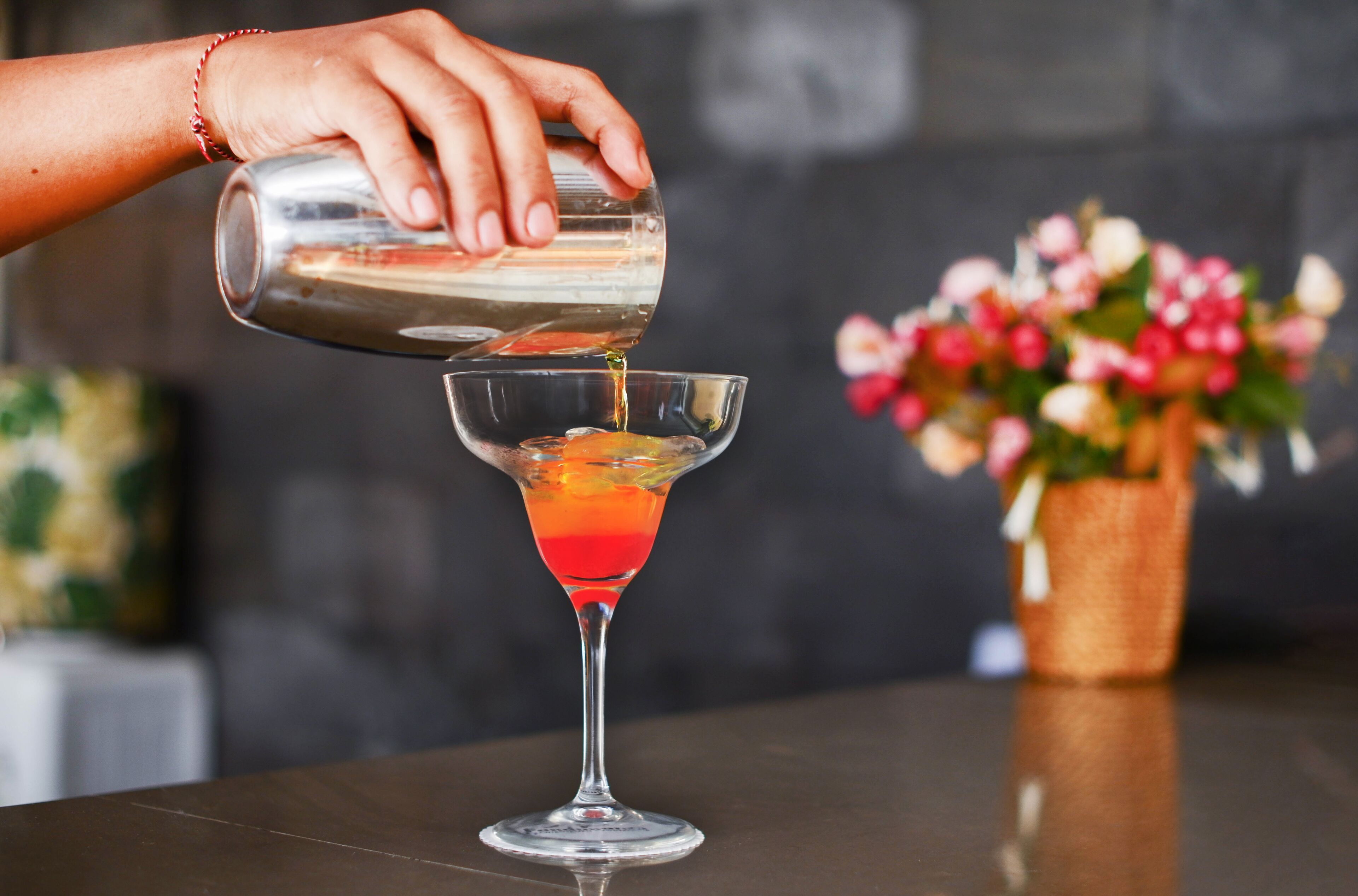 Una mano vertiendo una bebida en una copa de martini.