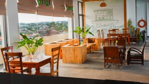 A modern cafe with wooden furniture, large windows, and a city view. - Pandanaran Prawirotaman Yogyakarta (Yogyakarta)