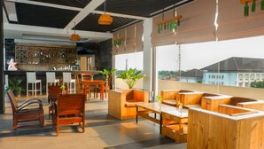 A modern bar area with wooden furniture and a view of buildings outside. - Pandanaran Prawirotaman Yogyakarta (Yogyakarta)