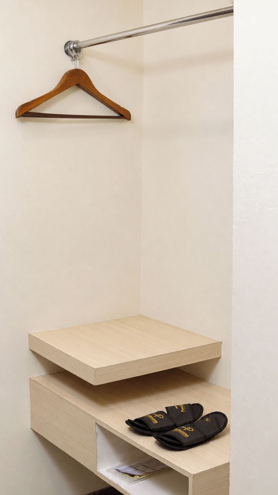 A wooden shelf with a pair of black slippers on it.
