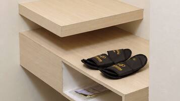 A wooden shelf with a pair of black slippers on it.