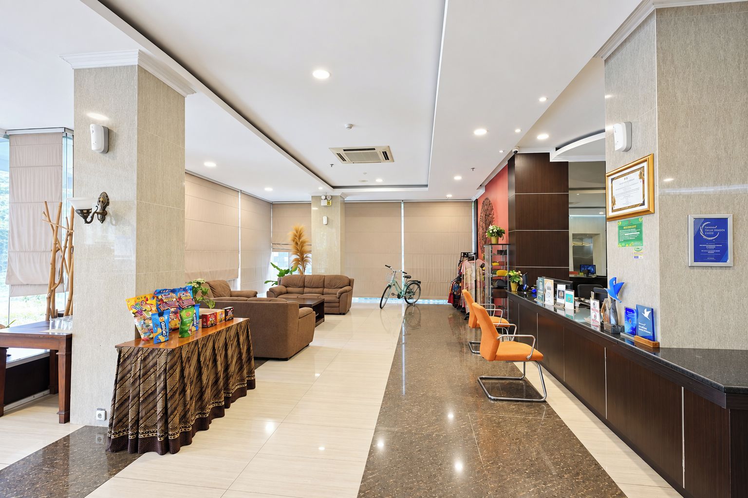 A hotel lobby with a reception desk, seating area, and a bicycle.