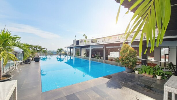 A rooftop pool with clear blue water, surrounded by potted plants and outdoor furniture. - Pandanaran Prawirotaman Yogyakarta (Yogyakarta)
