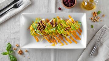 A white rectangular plate with a salad on a textured surface.