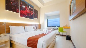 A hotel room with a large bed, a desk, a chair, and a view of the city. - Pandanaran Prawirotaman Yogyakarta (Yogyakarta)