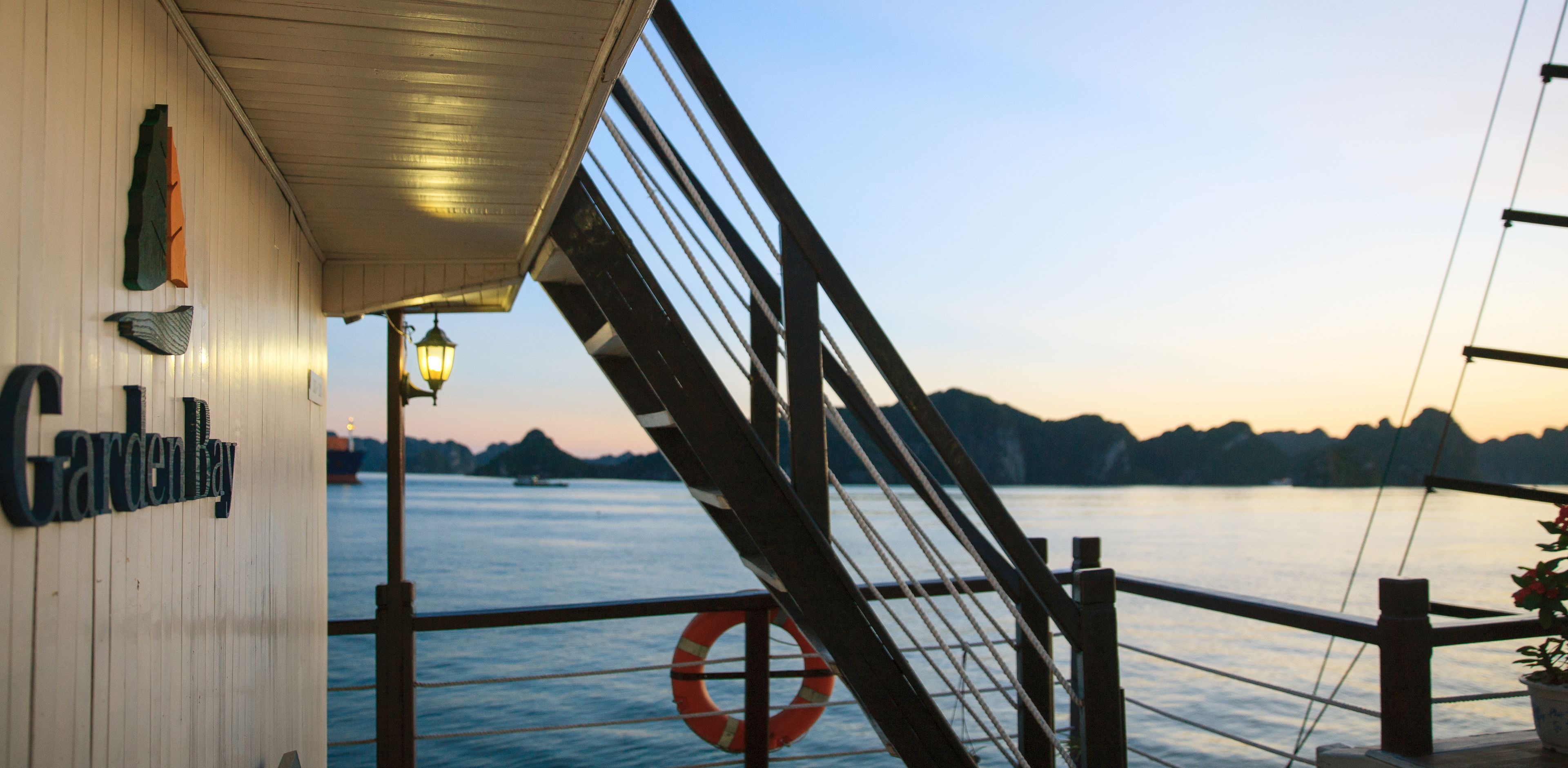 A view from a boat with a railing, a lifebuoy, and a sign reading "Gardenway".