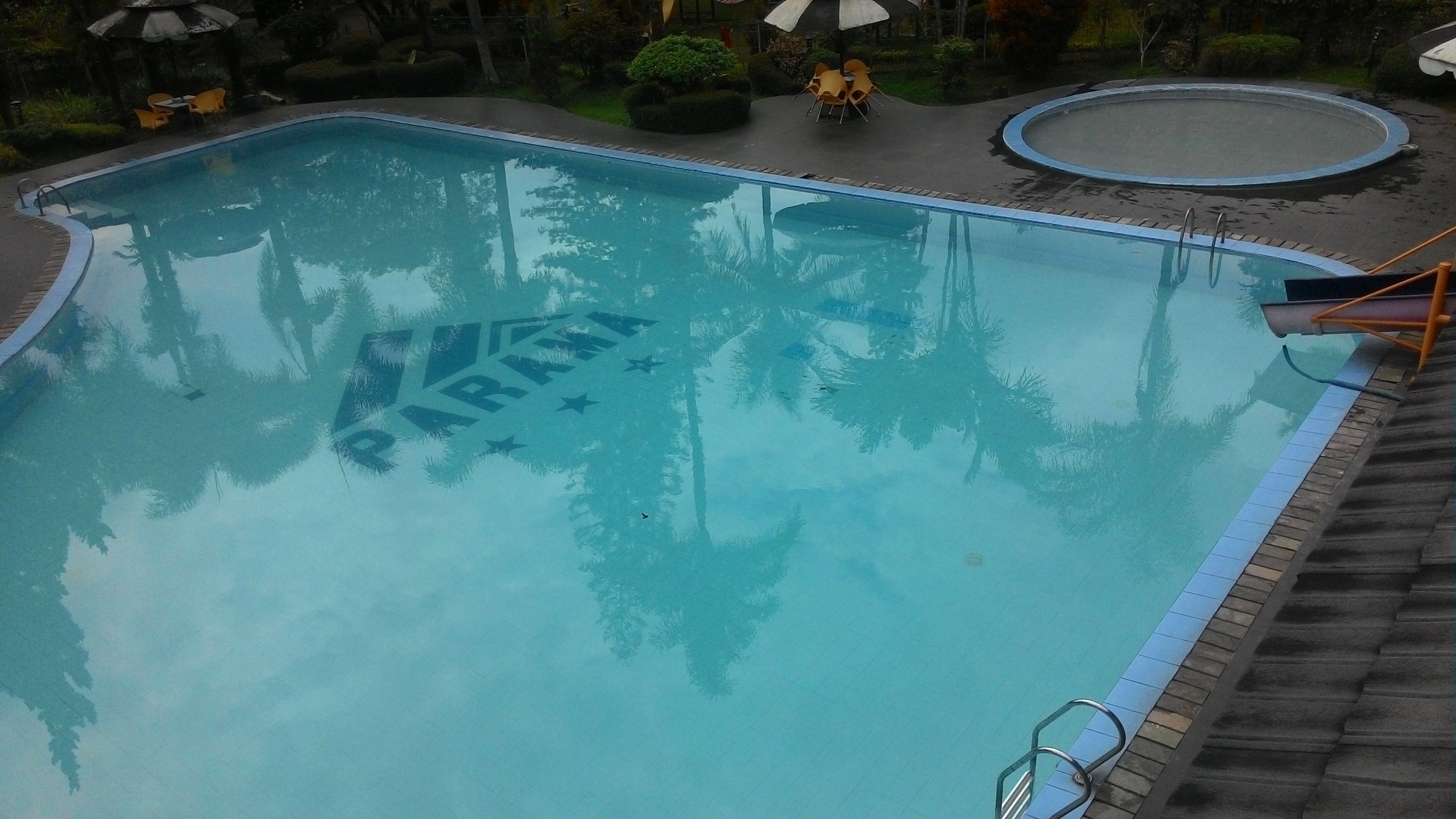 A swimming pool with a 'PARIS' inscription and surrounding lounge area with chairs and umbrellas.