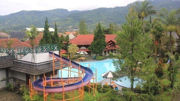 Un resort con piscina, tobogán de agua y vistas a las montañas.