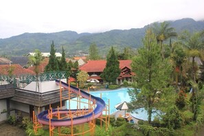 Un resort con piscina, tobogán de agua y vistas a las montañas.