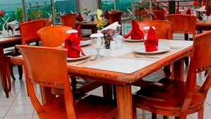 Un restaurante con mesas y sillas de madera, grandes ventanales y vistas a las montañas.