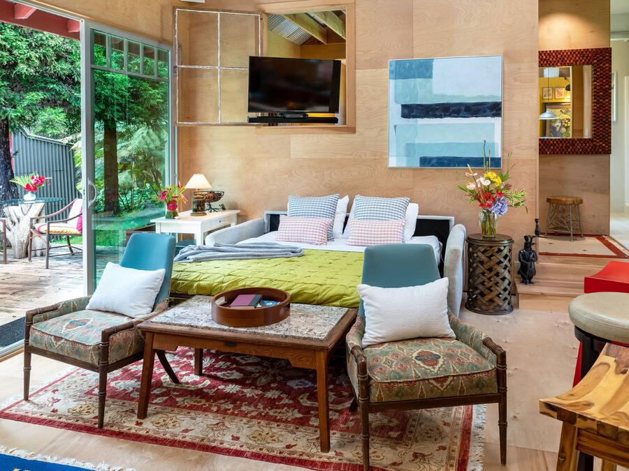 Amplia sala de estar con una cama grande, varias opciones de asientos, un televisor y vistas a zonas verdes.