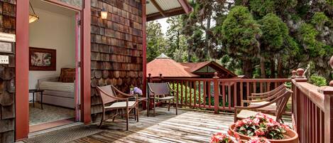 A wooden deck with outdoor furniture, a covered area, and potted plants.