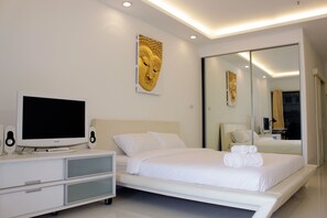 Un dormitorio moderno con una cama grande, un televisor de pantalla plana, parlantes y una estatua de Buda montada en la pared.