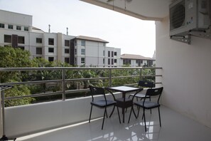 A balcony with a table and chairs, overlooking a residential area with modern buildings and greenery. - View Talay 3 Beach Apartments (Pattaya)