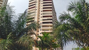 A high-rise building with multiple balconies and a dense arrangement of palm trees in the foreground. - View Talay 3 Beach Apartments (Pattaya)