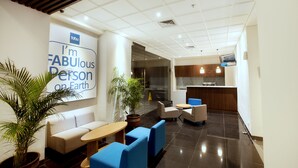 Eine moderne Lobby mit Sitzgelegenheiten, einem Empfangsbereich und einem großen Schild mit der Aufschrift 'I'm fabulous on Earth'.