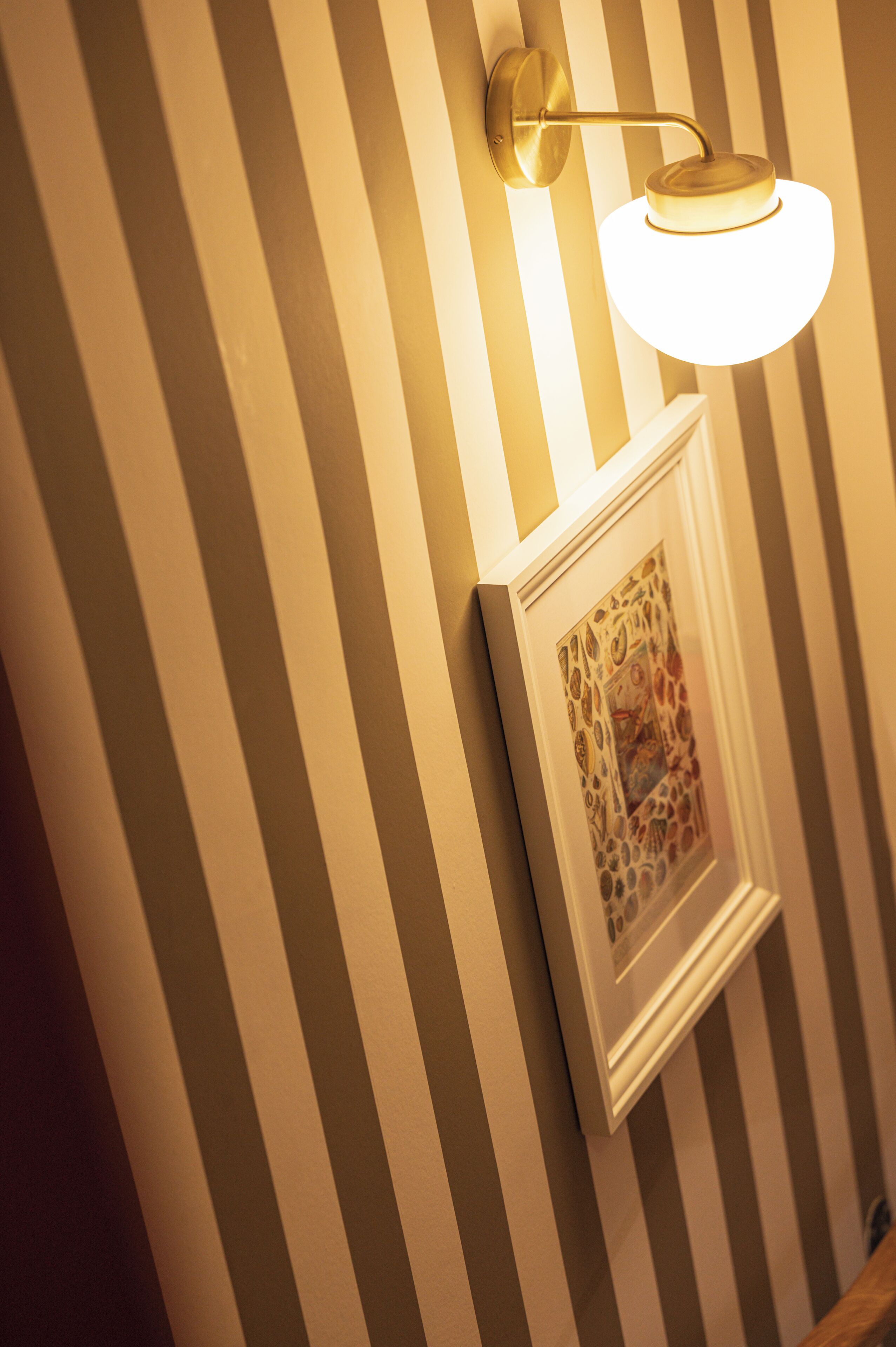 A wall with vertical stripes and a framed picture.