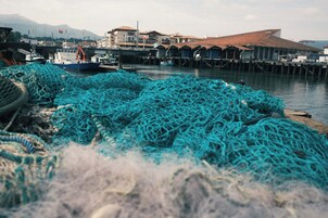 Un puerto con redes de pesca, barcos y edificios.