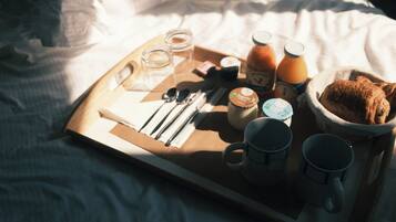 A breakfast tray on a bed with a dog bed in the corner.