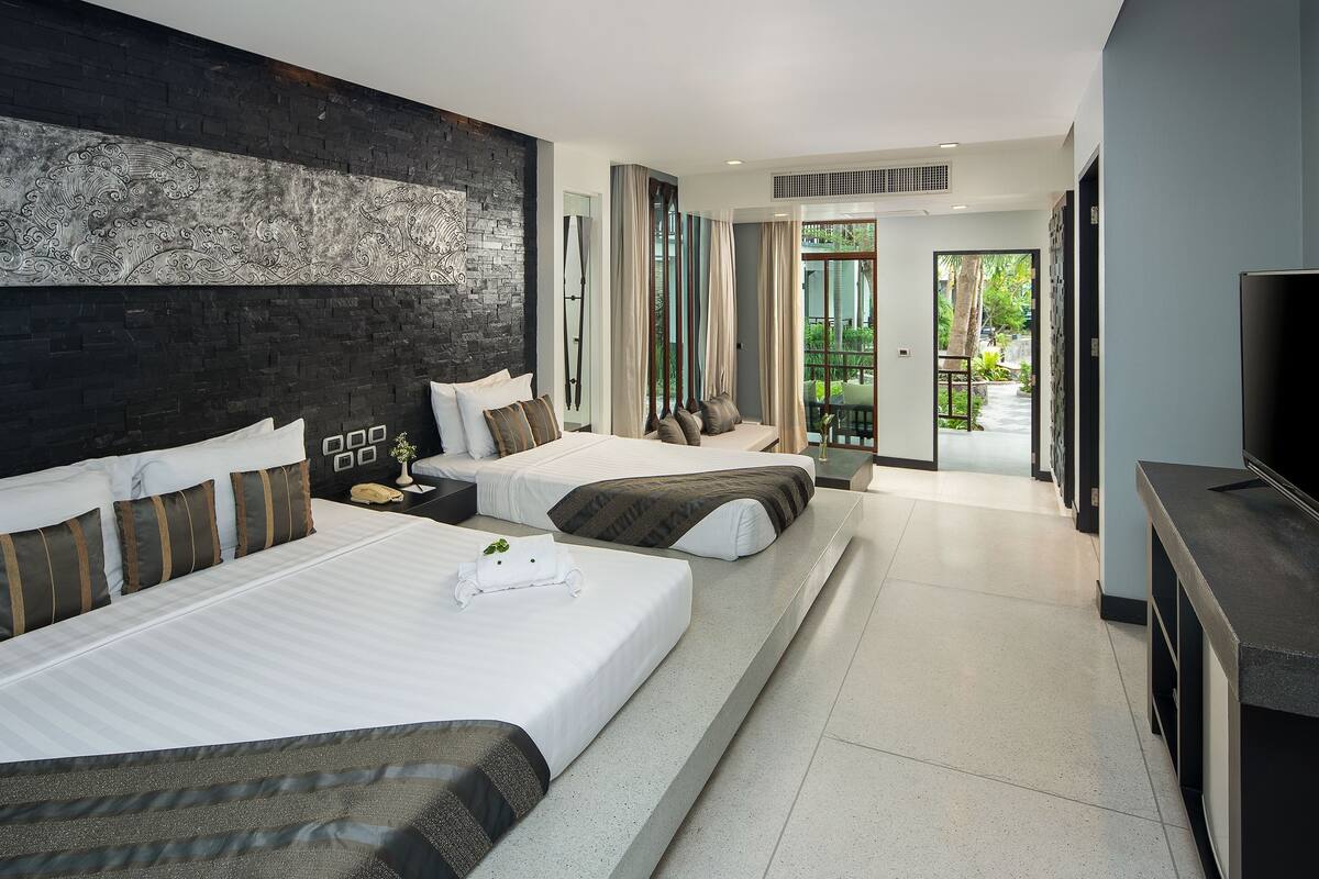 A modern hotel room with two beds, a large mirror, a TV, and a balcony with a view.