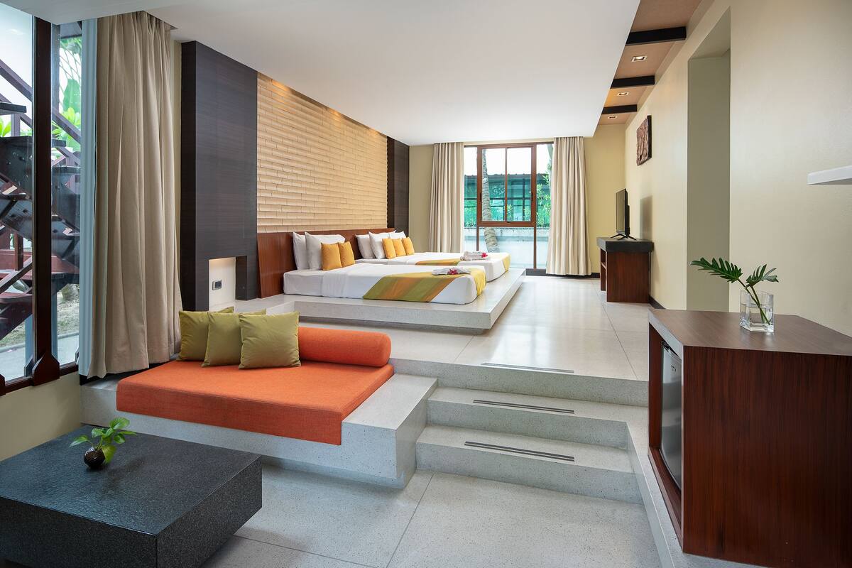 A modern hotel room with a large bed, a sofa, a desk, and a view of the outdoors.