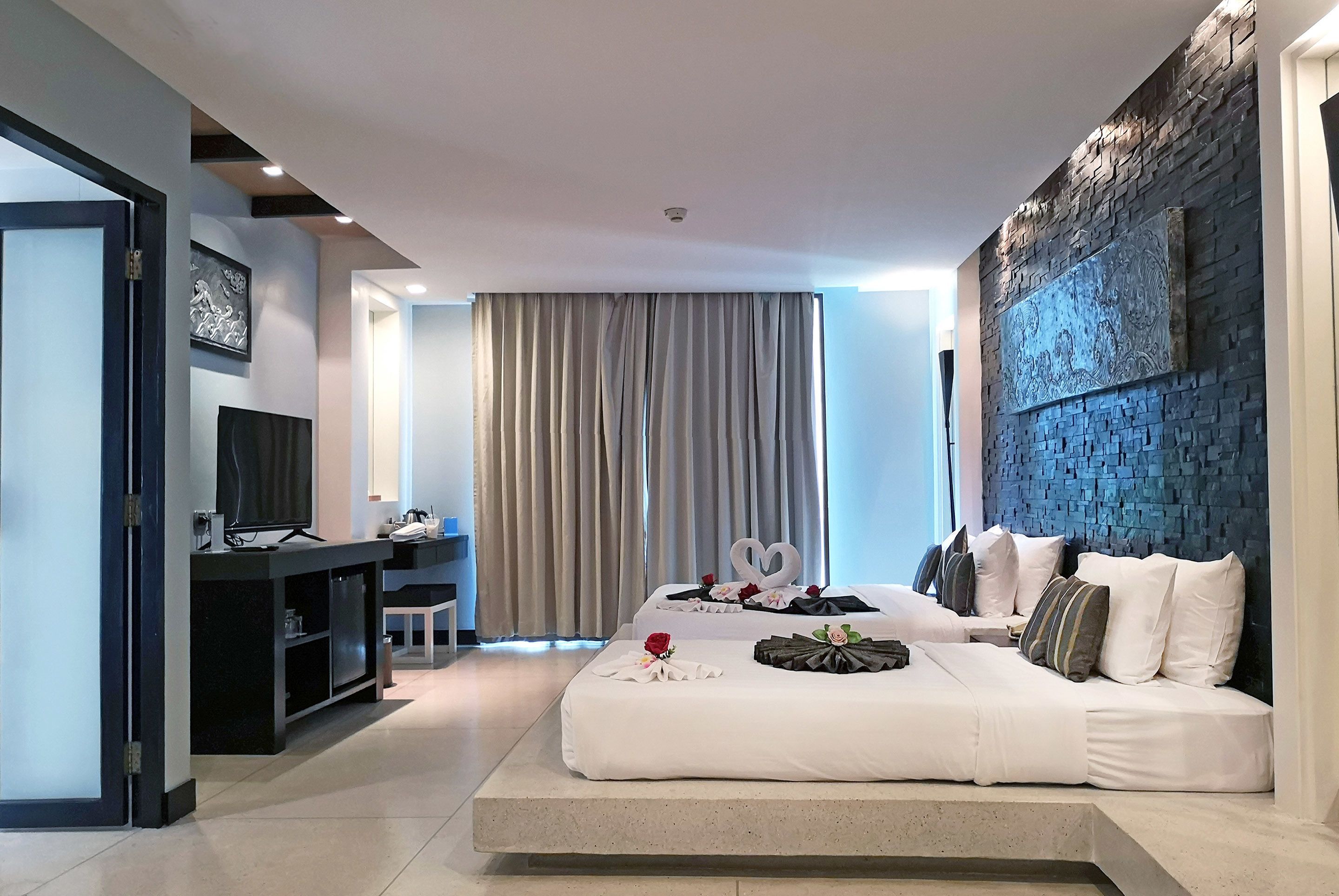 A modern hotel room with a large bed, a desk, and a television.