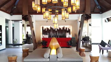 A reception area with a modern chandelier, a reception desk, and a seating area with a unique sculptural centerpiece.